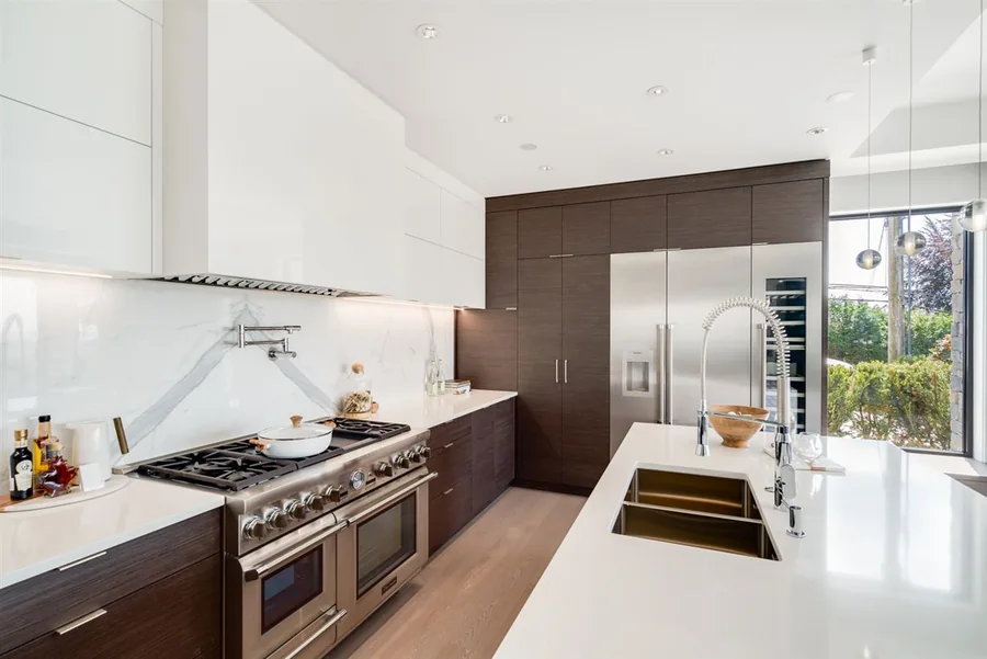 Kitchen with wood cabinetry, a long pale island and an undermount sink.