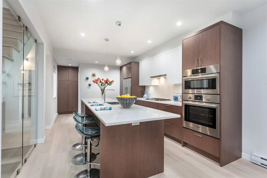 Kitchen with brown cabinetry, a central island and a vase of flowers.