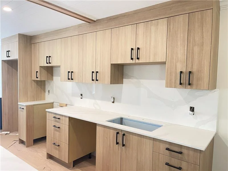 Kitchen with wood grain cabinet fronts and a long pale work surface.
