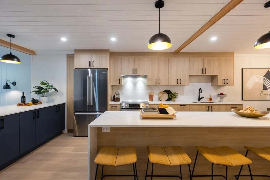 Kitchen island with wood cabinetry, yellow stools and dark blue base cabinets.